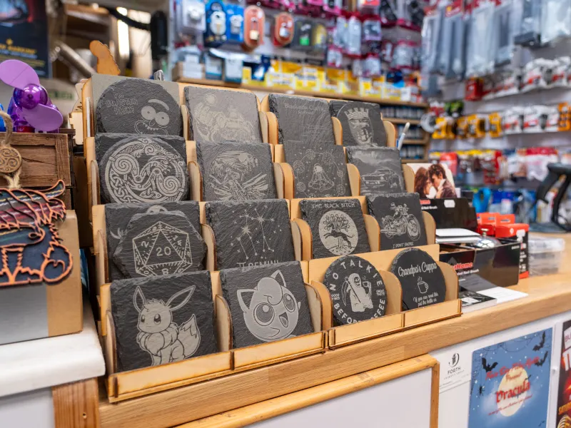 Engraved slate coasters in wooden display stands on the shop counter