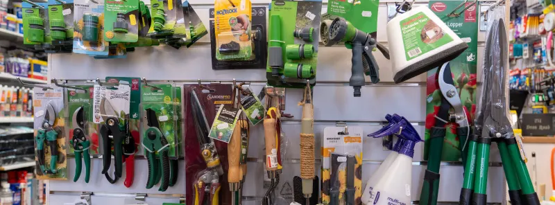 Garden tools on a pegboard: pruning shears, secateurs, hedge shears and hose fittings
