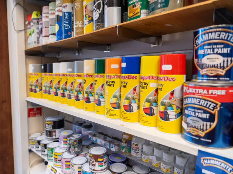 A shelf of spray paint and Hammerite metal paint tins